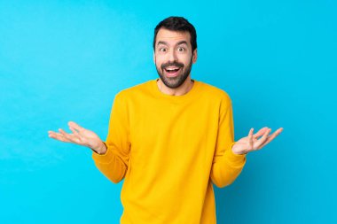 Yüzünde şok ifadesi olan, izole edilmiş mavi bir geçmişi olan beyaz bir genç.