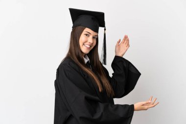 İzole edilmiş beyaz arka planda Brezilyalı genç üniversite mezunu. Davet edilmek için ellerini yana uzatıyor.