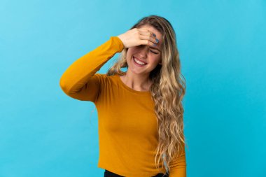 Genç Brezilyalı kadın mavi arka planda yalnız gülüyor.