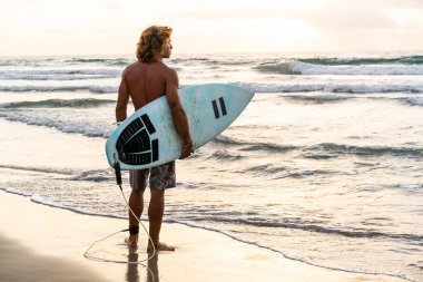 Kafkasyalı genç adam gün doğumunda sörf yapmak için erken kalkar.