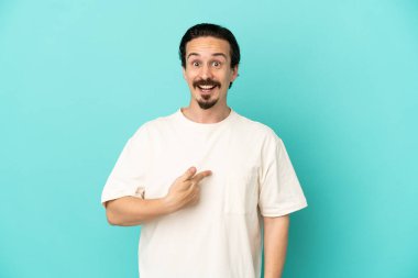 Mavi arka planda yalıtılmış beyaz bir adam. Şaşırtıcı bir yüz ifadesi var.