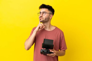 Elinde uzaktan kumandayı tutan adam sarı arka planda izole edilmiş şüpheleri olan ve düşünen biri.