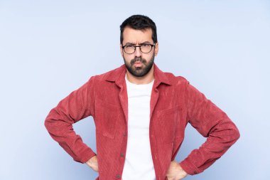 Mavi arka planda kadife ceket giyen genç, beyaz bir adam kızgın.