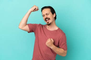 Mavi arka planda izole edilmiş beyaz bir adam zaferi kutluyor.