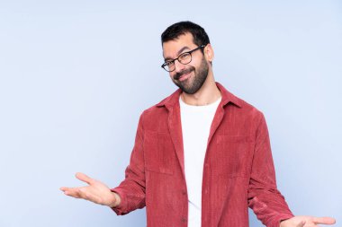 Mavi arka planda kadife ceket giyen genç beyaz adam gülümsüyor.