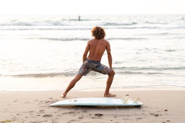 Kafkasyalı genç adam gün doğumunda sörf yapmak için erken kalkar.