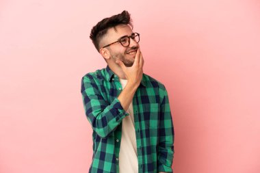 Pembe arka planda izole edilmiş genç beyaz adam gülümserken yukarı bakıyor.