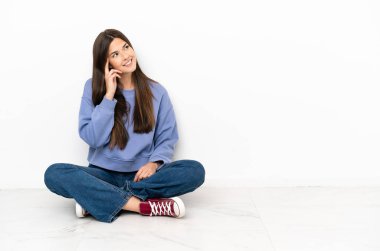 Genç bir kadın yerde oturmuş, yukarı bakarken bir fikir düşünüyor.