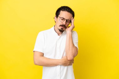 Sarı arka planda başağrısı olan genç beyaz bir adam izole edilmiş.