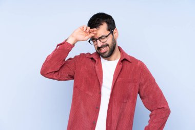 Mavi arka planda kadife ceket giyen genç beyaz adam yorgun ve hasta bir ifade takınıyor.