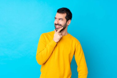 İzole edilmiş mavi arka planda gülümseyen genç beyaz bir adam.