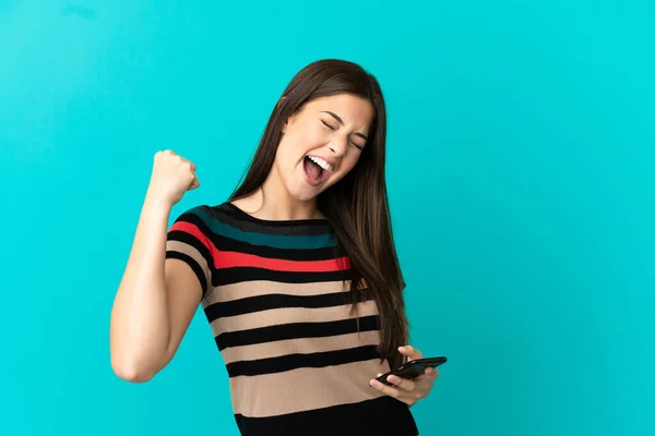 Adolescente Brésilienne Sur Fond Bleu Isolé Avec Téléphone Position Victoire — Photo