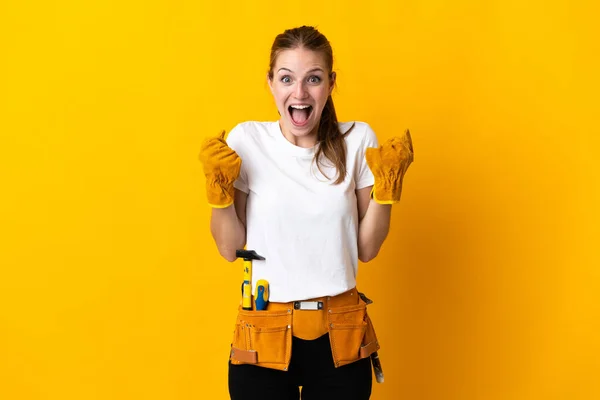 Young electrician woman isolated on yellow background celebrating a victory in winner position