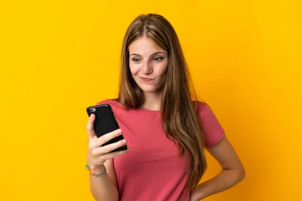 Ung Kvinna Som Använder Mobiltelefon Isolerad Gul Bakgrund Med Sorgligt — Stockfoto