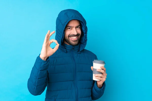 Uomo Indossando Giacca Invernale Tenendo Caffè Asporto Isolato Sfondo Blu — Foto Stock
