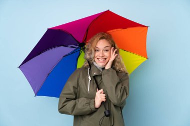 Mavi arka planda şemsiye tutan kadın