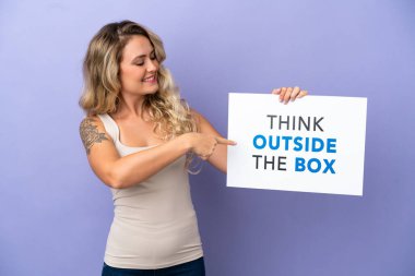 Mor arka planda izole edilmiş genç Brezilyalı bir kadın elinde yazılı bir levhayla Kutunun Dışını Düşün ve onu göster