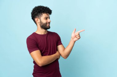 Faslı genç bir adam mavi arka planda izole edilmiş.