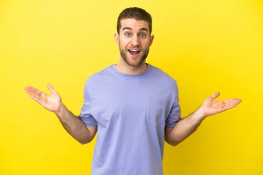 Sarışın yakışıklı, yalıtılmış sarı arka plan ve şok olmuş yüz ifadesi.