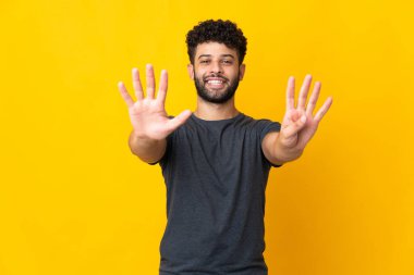 Sarı arka planda izole edilmiş genç Faslı dokuz parmağıyla sayıyor.