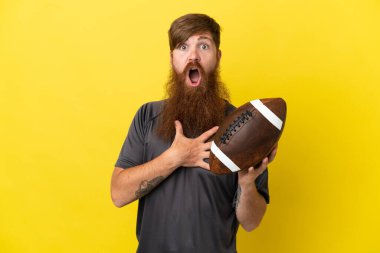 Kızıl saçlı beyaz adam sarı arka planda ragbi oynuyor. 