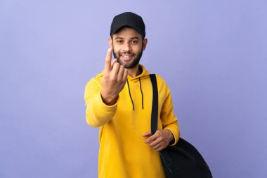 Spor çantalı genç Faslı adam mor arka planda izole edilmiş bir şekilde geliyor.