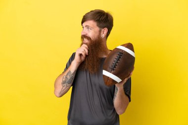 Kızıl saçlı beyaz adam sarı arka planda ragbi oynuyor. 