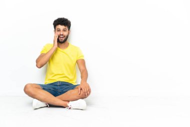 Genç Faslı yakışıklı bir adam yerde izole edilmiş bir zeminde oturuyor. Şaşırmış ve şok olmuş bir yüz ifadesi var.