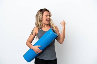 Genç Brezilyalı spor kadını yoga derslerine giderken beyaz arka planda izole edilmiş bir minderi tutarak zaferi kutluyor.