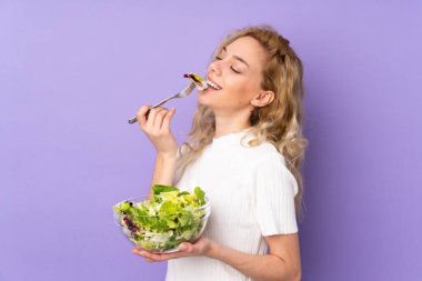 Mor arka planda salata tutan genç sarışın kadın.