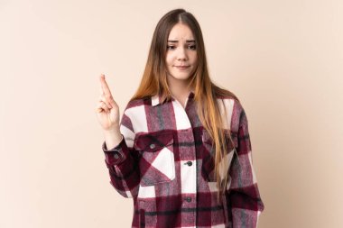 Beyaz tenli genç bir kadın, bej arka planda izole edilmiş, şans diliyor ve en iyisini diliyor.