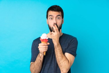 Kornet dondurması olan genç bir adam mavi arka planda, sağa bakarken şaşırmış ve şok olmuştu.