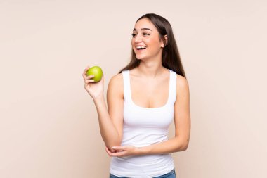 Beyazlı genç bir kadın bej arka planda yalnız ve mutlu.