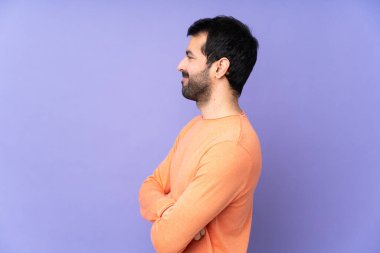 Kafkasyalı yakışıklı adam mor arka planda, yan pozisyonda.