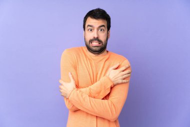 Kafkasyalı yakışıklı adam soyutlanmış mor arka planda donuyor.