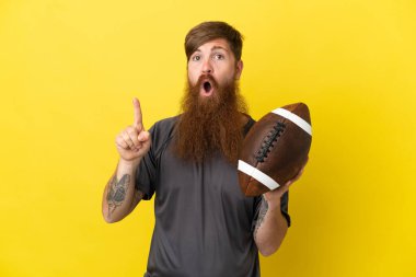 Kızıl saçlı beyaz adam sarı arka planda ragbi oynuyor. 