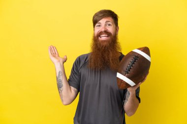 Kızıl saçlı beyaz adam sarı arka planda ragbi oynuyor. 