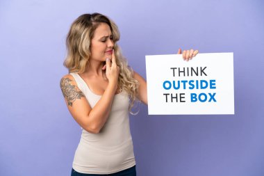 Mor arka planda izole edilmiş genç Brezilyalı bir kadın elinde yazılı bir levhayla Kutunun Dışını Düşün ve düşün