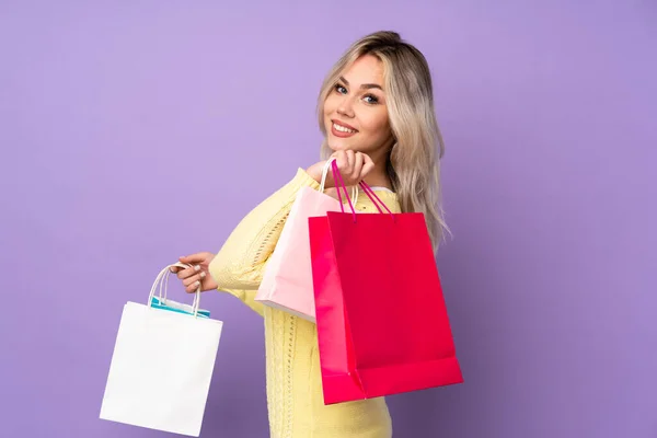 Tiener Blond Meisje Geïsoleerde Paarse Achtergrond Holding Shopping Tassen Glimlachen — Stockfoto