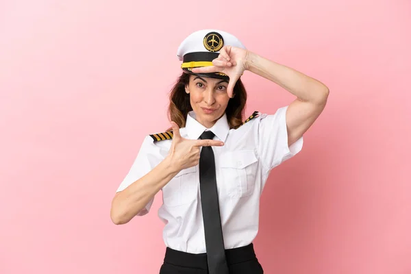 Airplane middle aged pilot woman isolated on pink background focusing face. Framing symbol