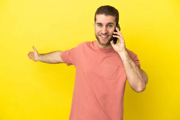 Przystojny Blondynka Człowiek Pomocą Telefonu Komórkowego Odosobnionym Tle Wyciągając Ręce — Zdjęcie stockowe