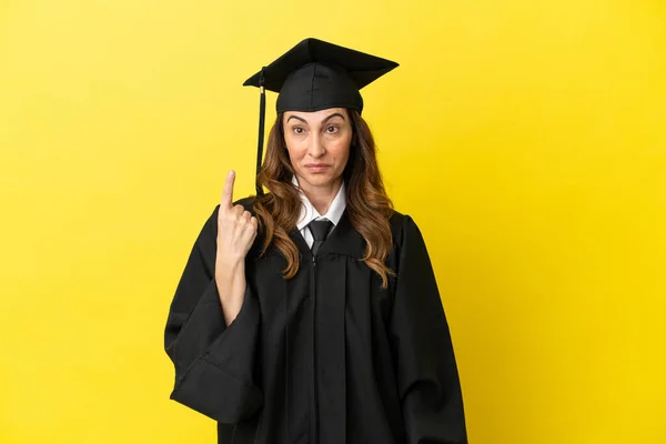 中高年大学の卒業生は 指標の指で指摘黄色の背景に孤立素晴らしいアイデア — ストック写真
