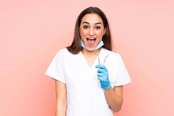 Zahnärztin Hält Werkzeuge Isoliert Auf Rosa Hintergrund Mit Überraschendem Gesichtsausdruck — Stockfoto