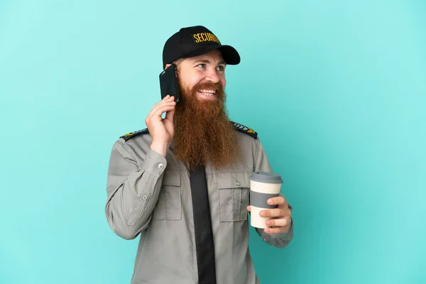 Redhead security man isolated on white background holding coffee to take away and a mobile