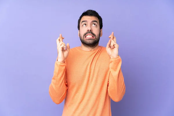 Blanke Knappe Man Geïsoleerde Paarse Achtergrond Met Vingers Kruisen Wensen — Stockfoto