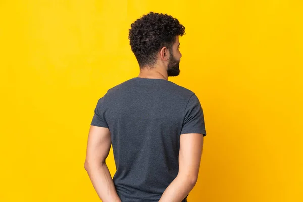 Joven Hombre Marroquí Aislado Sobre Fondo Amarillo Posición Trasera Mirando — Foto de Stock