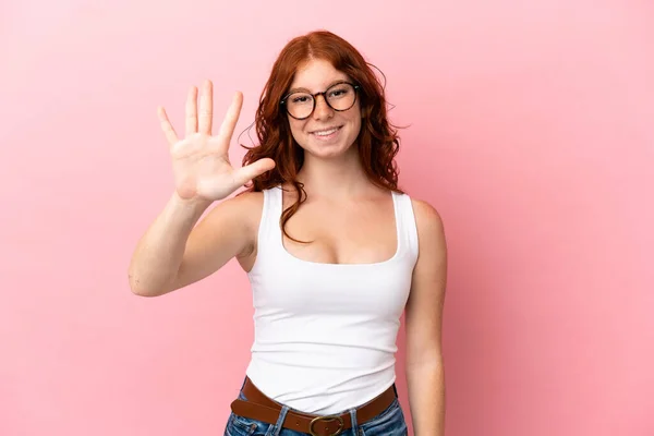 ピンクの背景に5本指で数える10代の赤女性 — ストック写真