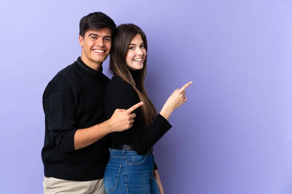 Giovane Coppia Sfondo Viola Isolato Puntando Dito Verso Lato Presentando — Foto Stock