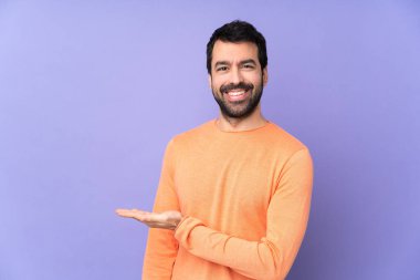 Kafkasyalı yakışıklı bir adam soyutlanmış mor arka planda bir fikir sunuyor ve gülümsüyor.