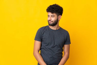 Faslı genç bir adam sarı arka planda izole edilmiş. Taraf tutarken şüphe duyuyor.
